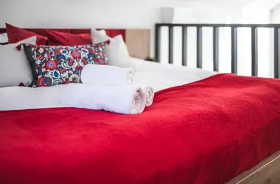 a bed with two towels on a red blanket at Domki pod Krakowem - Stare Sady in Kopytówka
