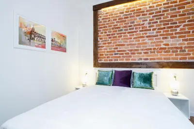 a bedroom with a white bed with a brick wall at Apartment for two-Jewish Quarter-Starowiślna 54 in Kraków
