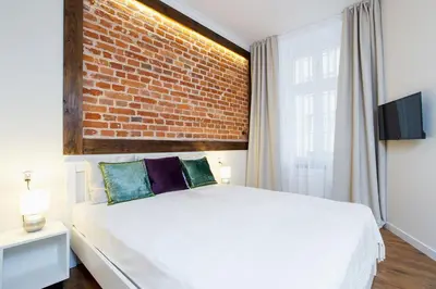 a bedroom with a white bed with a brick wall at Apartment for two-Jewish Quarter-Starowiślna 54 in Kraków