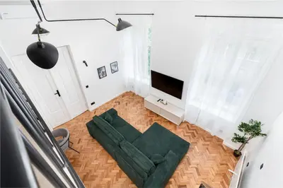 a living room with a green couch and a television at Old Town Apartment with Mezzanine by BookingHost in Kraków