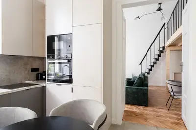 a kitchen with white cabinets and a table and chairs at Old Town Apartment with Mezzanine by BookingHost in Kraków