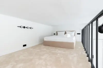 a white bedroom with a bed and a staircase at Old Town Apartment with Mezzanine by BookingHost in Kraków