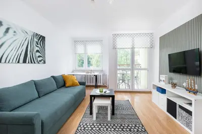 a living room with a blue couch and a tv at Olsza Comfy Apartment by BookingHost in Kraków