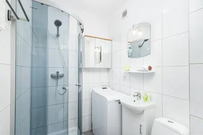 a white bathroom with a shower and a toilet and a sink at Olsza Comfy Apartment by BookingHost in Kraków