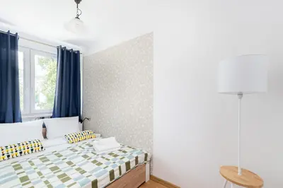 a bedroom with a bed with blue curtains and a window at Olsza Comfy Apartment by BookingHost in Kraków