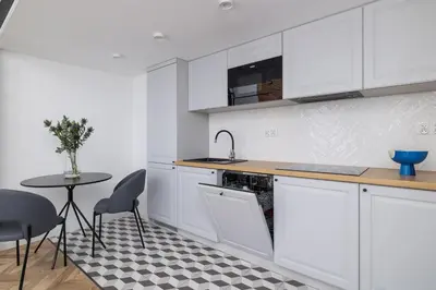 a kitchen with white cabinets and a table with chairs at Balcony Apartment - Kazimierz- Starowiślna 41 in Kraków