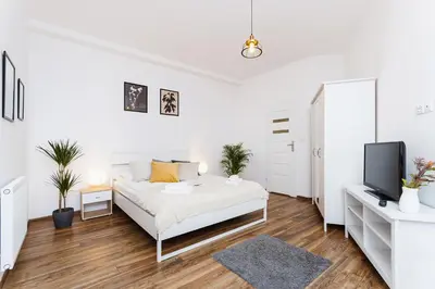 a white bedroom with a bed and a tv at Studio for two - Starowiślna 54 in Kraków