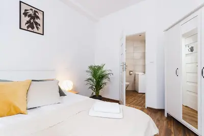a white room with a white bed and a bathroom at Studio for two - Starowiślna 54 in Kraków