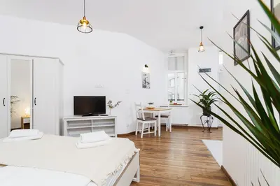 a white apartment with two beds and a table at Studio for two - Starowiślna 54 in Kraków