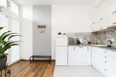 a white kitchen with white cabinets and a wooden floor at Studio for two - Starowiślna 54 in Kraków