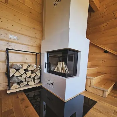 a fireplace in a log cabin with wooden walls at Casa Viento in Stryszawa