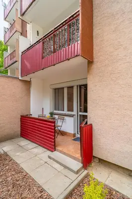a house with a red fence and a balcony at Kraków Czyżyny - Terrace by Rentujemy in Kraków