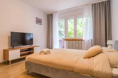 a bedroom with a bed and a flat screen tv at Kraków Czyżyny - Terrace by Rentujemy in Kraków