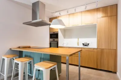 a kitchen with wooden cabinets and a wooden table and stools at Przestronny apartament Vermelo Parking in Kraków
