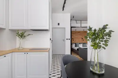 a kitchen with white cabinets and a table with plants at Kazimierz - Balcony Apartment - 41 Starowislna Street in Kraków