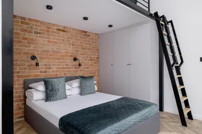 a bedroom with a bed with a brick wall at Kazimierz - Balcony Apartment - 41 Starowislna Street in Kraków