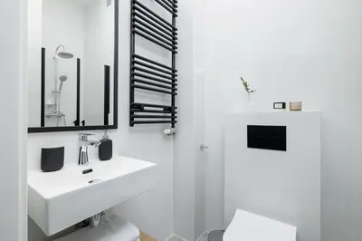 a white bathroom with a sink and a mirror at Kazimierz - Balcony Apartment - 41 Starowislna Street in Kraków