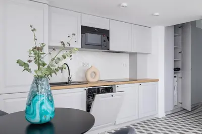 a kitchen with white cabinets and a vase with flowers on a table at Apartment with Balcony - 41 Starowislna Street in Kraków