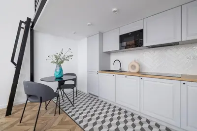 a kitchen with white cabinets and a table and chairs at Apartment with Balcony - 41 Starowislna Street in Kraków