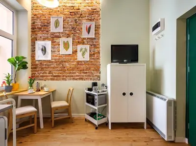 a living room with a table and a white refrigerator at Crocus narrow studio / Kochanowskiego in Kraków