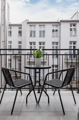 a table and chairs on a balcony with a building at Apartment with Balcony - Starowiślna 41 in Kraków