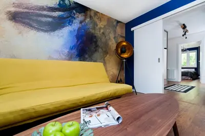 a living room with a yellow couch and a table at Charming Apartment with balcony, Jewish District in Kraków