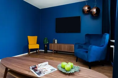 a blue living room with a table and a blue wall at Charming Apartment with balcony, Jewish District in Kraków