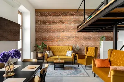 a living room with yellow furniture and a brick wall at Luxe Living Kazimierz with Patio in Kraków
