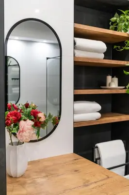 a mirror on a table with a vase with flowers at Luxe Living Kazimierz with Patio in Kraków