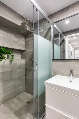 a bathroom with a glass shower and a sink at Luxe Living Kazimierz with Patio in Kraków