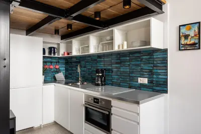 a kitchen with white cabinets and blue subway tiles at Luxe Living Kazimierz with Patio in Kraków