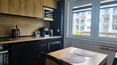 a kitchen with a wooden table and a counter and a table and a window at Apartment Bunscha Park in Kraków