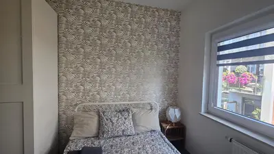 a bedroom with a wall with a bed and a window at Apartment Bunscha Park in Kraków