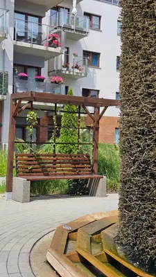 a wooden bench in front of a building at Apartment Bunscha Park in Kraków