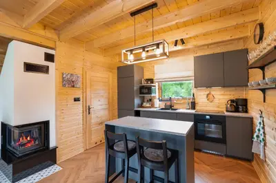 a kitchen with a fireplace in a log cabin at Wilczna Stodoła in Zawoja