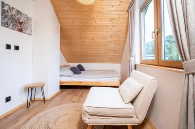 a room with a bed and a chair and a window at Wilczna Stodoła in Zawoja