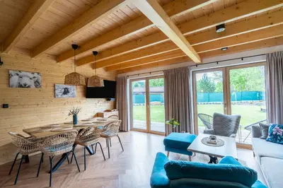 a dining room and living room with a table and chairs at Wilczna Stodoła in Zawoja