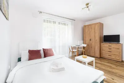 a white bedroom with a bed and a table at Czerwone Maki Studio with Garden by BookingHost in Kraków