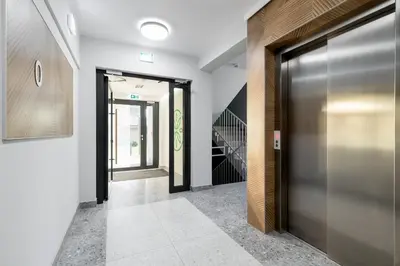 a hallway with a metal door and a staircase at Czerwone Maki Studio with Garden by BookingHost in Kraków
