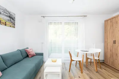 a living room with a blue couch and a table at Czerwone Maki Studio with Garden by BookingHost in Kraków