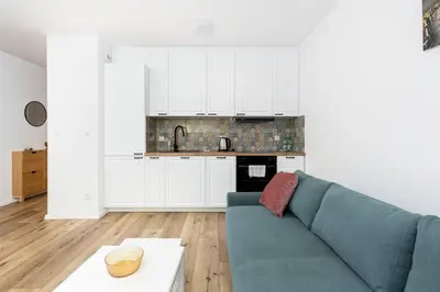 a living room with a blue couch and a kitchen at Czerwone Maki Studio with Garden by BookingHost in Kraków