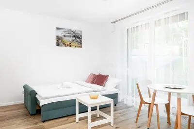 a small white room with a bed and a table at Czerwone Maki Studio with Garden by BookingHost in Kraków