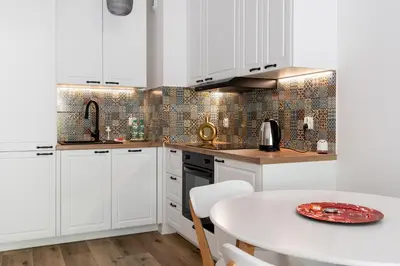 a kitchen with white cabinets and a white table at Czerwone Maki Apartment with Garden by BookingHost in Kraków