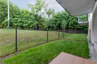 a fence in front of a field with trees at Czerwone Maki Apartment with Garden by BookingHost in Kraków
