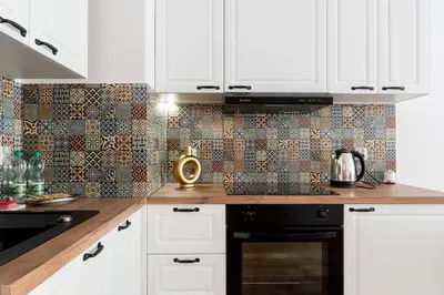 a kitchen with white cabinets and a tile wall at Czerwone Maki Apartment with Garden by BookingHost in Kraków