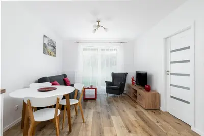a dining room and living room with a white table and chairs at Czerwone Maki Apartment with Garden by BookingHost in Kraków
