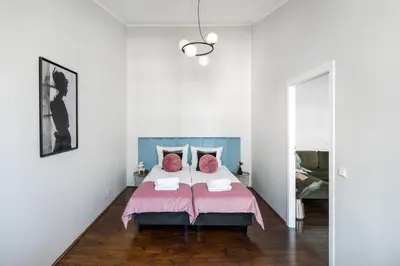 a bedroom with a large bed with pink sheets at GA Apartments in Kraków
