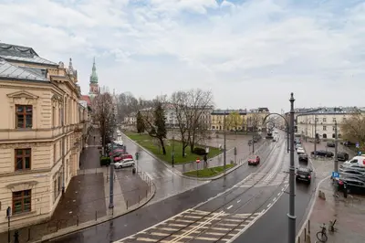 a city street in the rain with cars on the road at 3 Bedroom Apartment - Rynek Podgórski 15 in Kraków