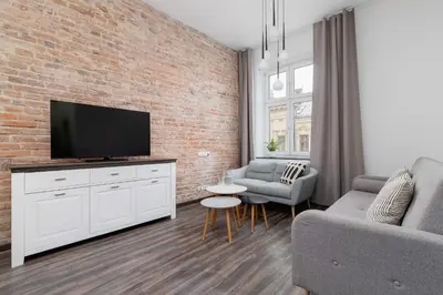 a living room with a tv and a brick wall at 3 Bedroom Apartment - Rynek Podgórski 15 in Kraków