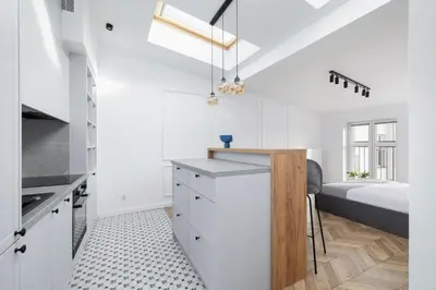a kitchen with white cabinets and a bed in a room at Studio with an AC - Kazimierz - Starowislna 41 in Kraków